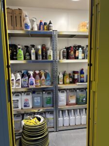 Inside portable cleaning storage cupboard showing shelving and organised cleaning products