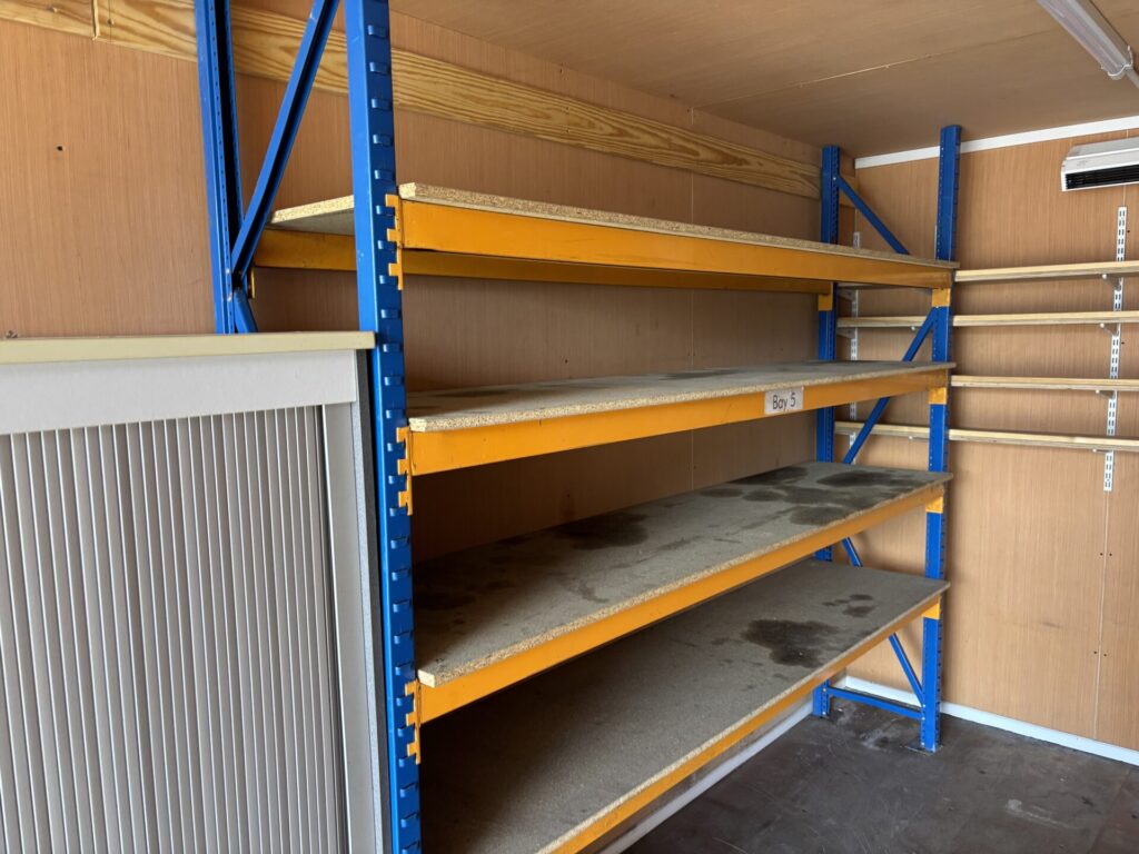 Heavy-duty longspan steel shelving fitted inside a 20ft insulated workshop container.